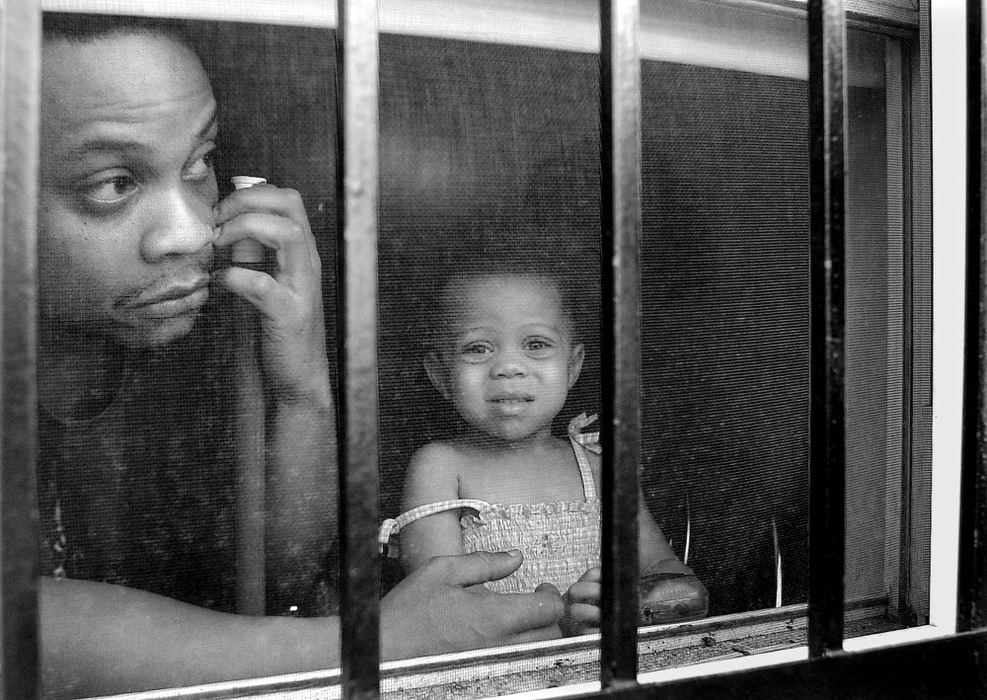 First Place, Team Picture Story -  / Cincinnati EnquirerPeering out from behind the protective bars of their own windows Marcus Johnson and his 2 year-old daughter Brianna look at the damage to the 1600 block of Race Street in the wake of rioting in Over-the-Rhine. 