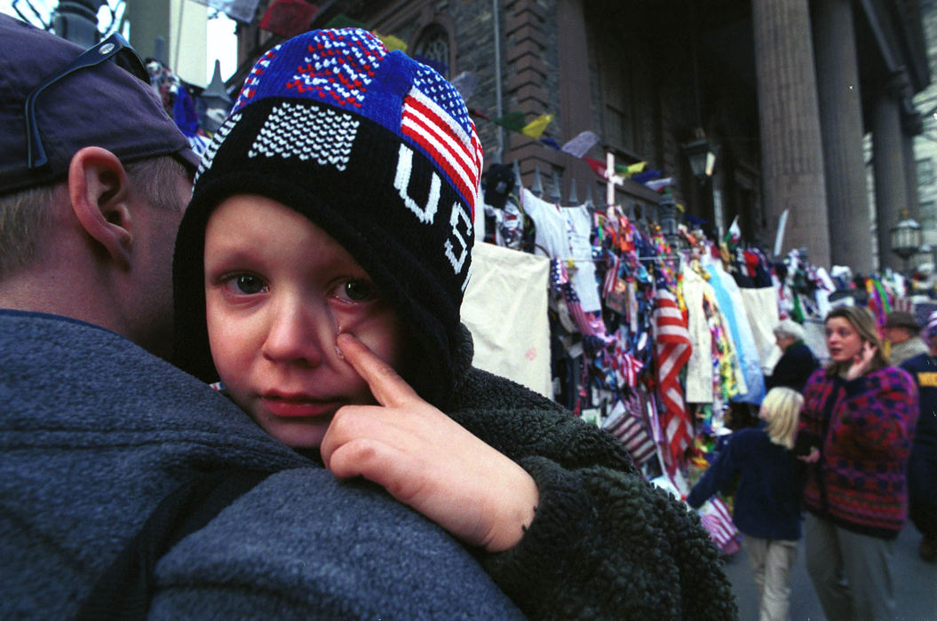 Award of Excellence, War on Terror - David Distelhorst / Ohio UniversityKyle Benbrook wipes away a tear at a memorial to the September 11 Terrorist Attacks outside of St. Paul's Chapel, New York City, Tuesday, December 11, 2001. Kyle, his father Kevin, left, and mother Sieglinde, right, visited the memorial near Ground Zero on the three month anniversary of the attack.