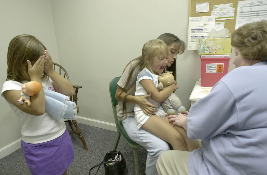 Award of Excellence, Assigned Feature - David Distelhorst / The AdvocateAurora Smith, 6, covers her eyes while her sister Lydia Wears, 5, gets a shot in the thigh at the Licking County Health Department, August 20, 2002.