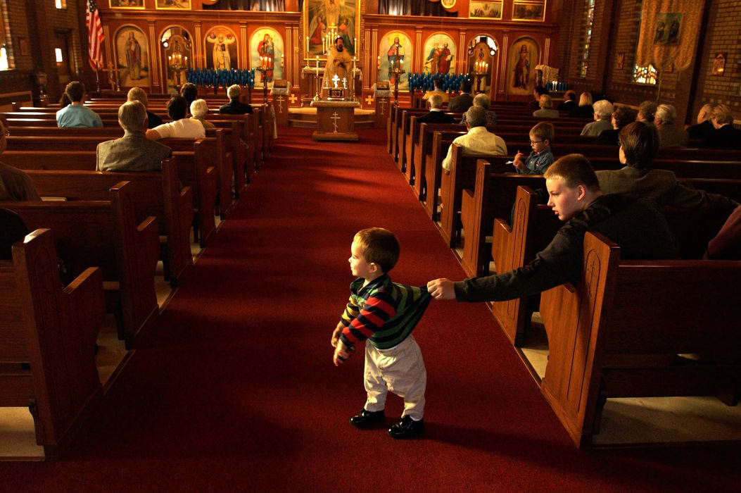 Award of Excellence, Assigned Feature - Jeff Greene / The Plain DealerJonathan Brown, 14, corrals Nathaniel Sawchak, 2, as  Nathaniel's father, Timothy, celebrates Mass at Saints Peter & Paul Russian Orthodox Church in Lakewood's Birdtown area.