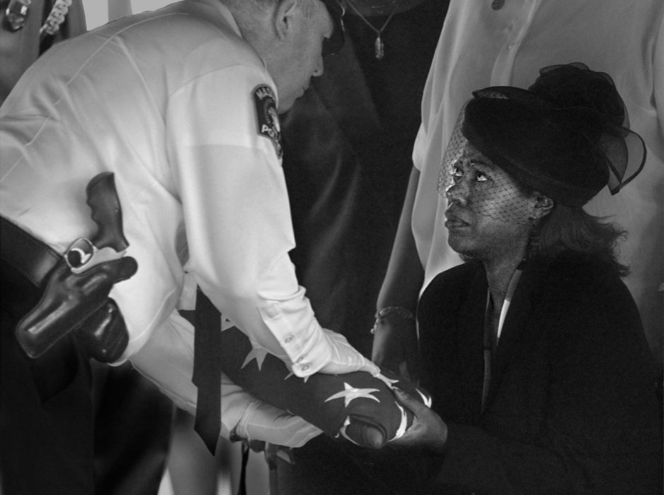 First Place, News Picture Story - Ed Suba, Jr. / Akron Beacon Journal(r) JuWanna Taylor, wife of slain Massillon police officer Eric Taylor, is presented the American flag that covered the casket of her husband during a memorial service at Mt. Peace Cemetery in Akron.