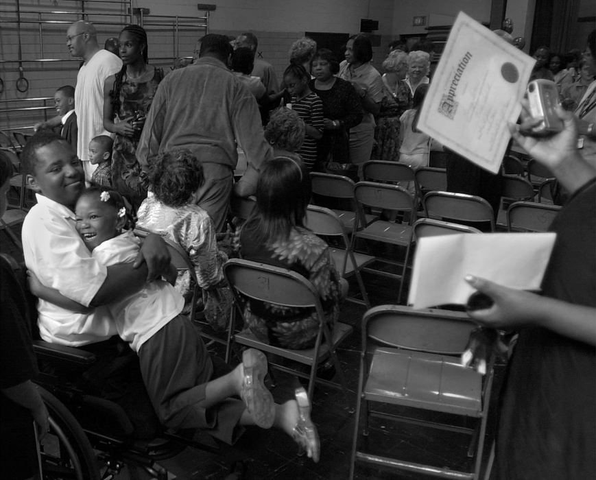 First Place, Ohio Understanding Award - Ed Suba, Jr. / Akron Beacon JournalLeroy Sutton gets a congratulatory hug from his sister, Keyaira, as he mother proudly inspects his "diploma" after he and his fifth grade class graduate from Case Elementary School in Akron.