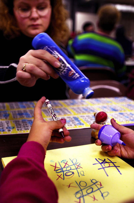 Third Place, Ohio Understanding Award - Steven M. Herppich / Cincinnati EnquirerBobbi Griffin, 30, of Forest Park has been coming to St. Boniface Bingo since she was 8 years old. She plays a game of tic-tac-toe with her daughter Tiffany, 6, while playing her bingo cards at Saint Boniface Church in Northside, January 24, 2002.  