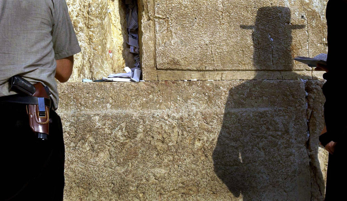 Third Place, Photographer of the Year - Dale Omori / The Plain DealerA man wears a handgun while praying at the Western Wall in the Old City of Jerusalem, Oct. 25, 2002, Israel.  