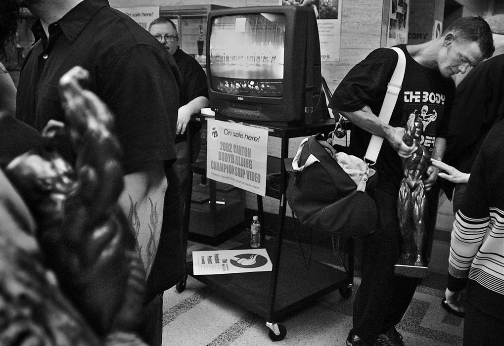 First Place, Photographer of the Year - Ed Suba, Jr. / Akron Beacon JournalThe contest over and the title won, a fan reaches out to touch the light heavyweight trophy held by Akron firefighter Doug Price at the end of the 2002 Canton Body building championship at Timken H.S. in Canton. Price's Mr. Canton overall trophy is at left.