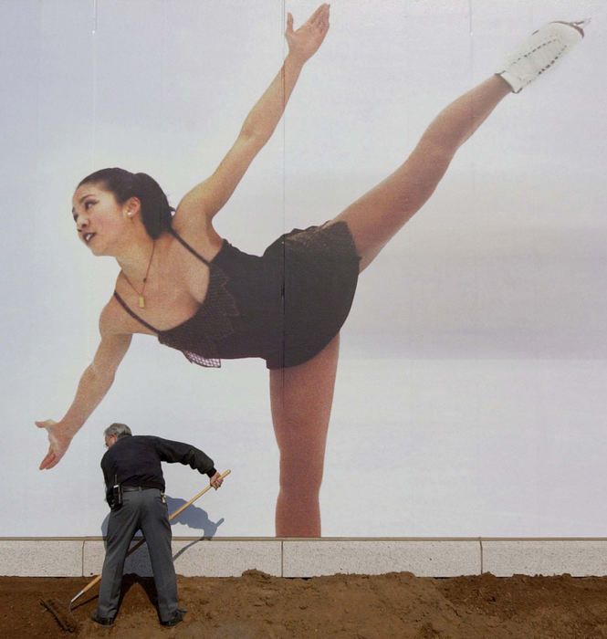 Second Place, Photographer of the Year - John Kuntz / The Plain DealerRick Mills, grounds supervisor at the Little America Grand Hotel, rakes fill dirt February 6, 2002 placed around the outside of the building near an enlarged mural of U.S. Olympic skater Michelle Kwan on his finishing touches of the property before the start of the 2002 Winter Olympic Games in Salt Lake City, Utah.    