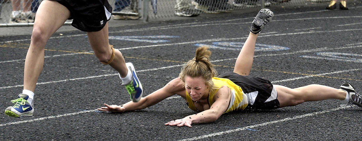 Second Place,  Sports Action - Bob Rossiter / The RepositorySt.Thomas Aquinas Julie Rentz falls after making the final exchange to anchor Amy Vagedes in the girls 4x100. Rentz's efforts paid off in a win for St. Thomas.