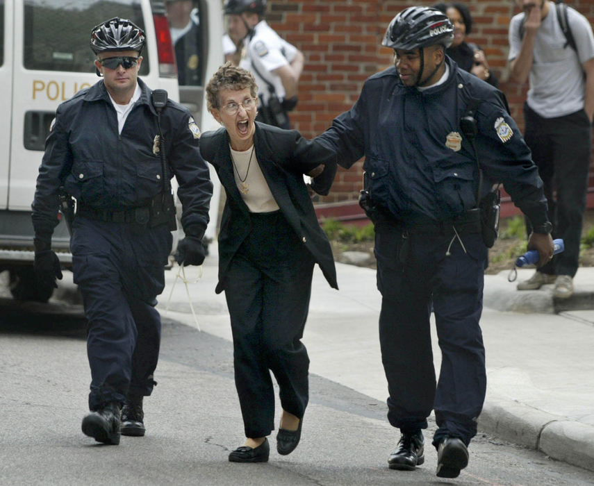 Second Place, Spot News over 100,000 - Neal C. Lauron / The Columbus DispatchPaula Ewers of Dayton is escorted by Columbus police officers after she was arrested from the lobby of Senator Mike DeWine for refusing to leave his office and resisting arrest. Her group was protesting and challenging DeWine's support for increased military support in the Latin American country of Columbia. Ewers was arrested with 9 other protesters.