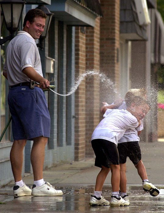 First Place, Student Photographer of the Year - James Patterson / Ohio UniversityAaron Lewis, 6, hides behind his brother Jarrett, 4, while their dad, Mike Lewis, sprays them. Mike was washing dirt and dust from road construction off the sidewalk in front of his building in downtown Findlay.