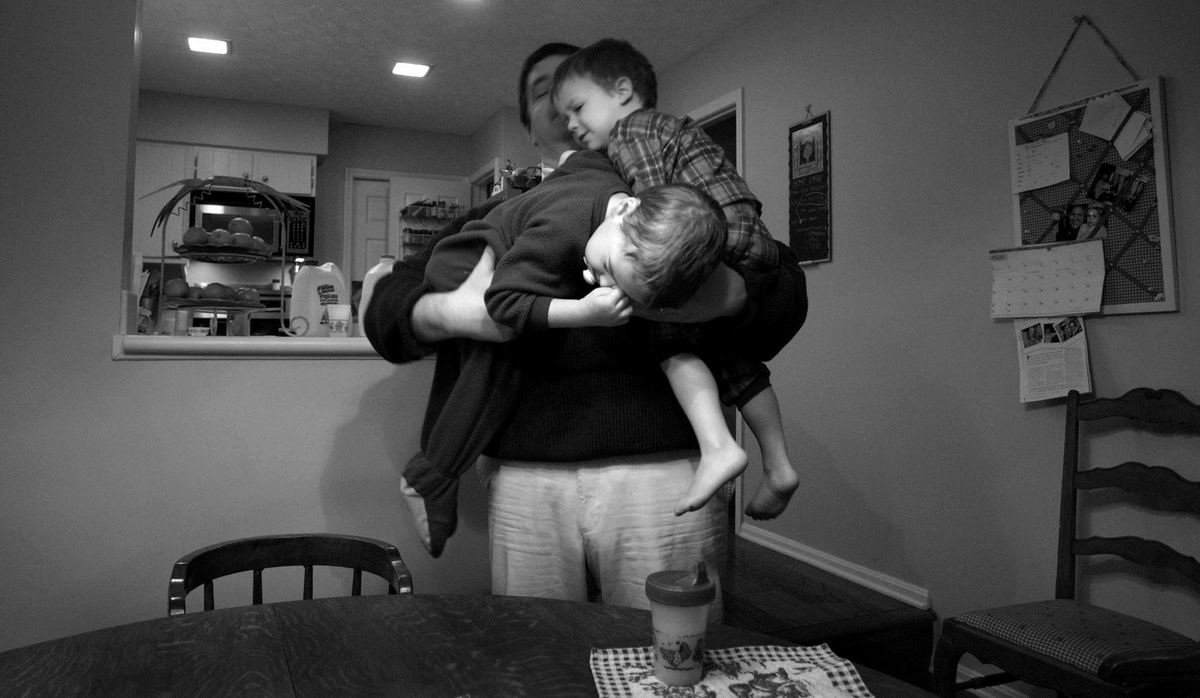 First Place, Feature Picture Story - Dale Omori / The Plain DealerMarc and Sophia Augier have four children; Marcel, 5, fraternal twins Henri and Christophe, 3, and daughtger Margaux, 2.  The three boys all suffer from autism.  Beyond the emotional and physical struggles of raising three autistic children, the Augiers also face steep financial hurdles.  They pay out-of-pocket more than $50,000 a year per child for speech and behavioral therapy at the Cleveland Clinic.  Fraternal twins Henri, left, and Christophe, are carried down to breakfast by father, Marc Augier. 