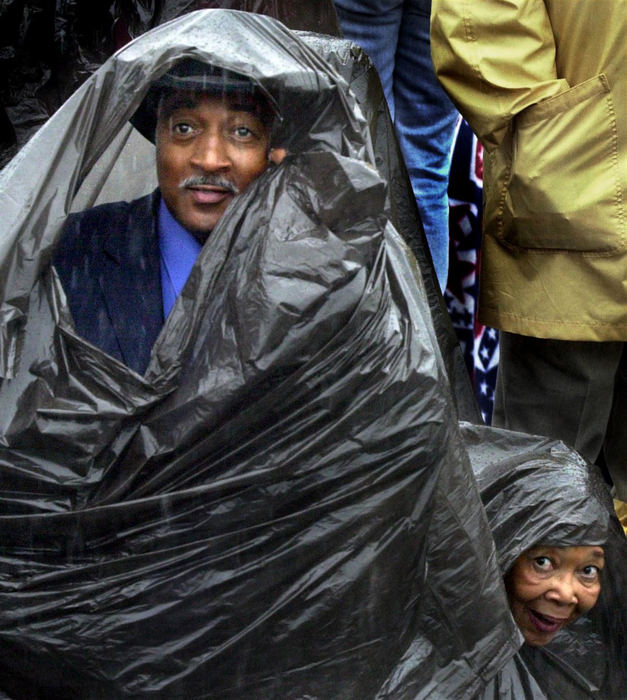 Award of Excellence, General News - Lynn Ischay / The Plain DealerOliver Richard Abernathy Jr. and Katie Bonner of Dayton try to keep dry as they watch President Bush approach the Ohio Operating Engineers Training Center. People were not allowed to carry umbrellas into the center.  