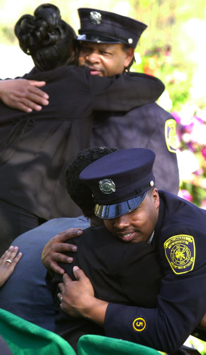 First Place, News Picture Story - Glenn Hartong / The Cincinnati EnquirerCincinnati firefighters hug Oscar Armstrong's fiancee, left, and mother right following his burial at Spriong Grove Cemetery.                              