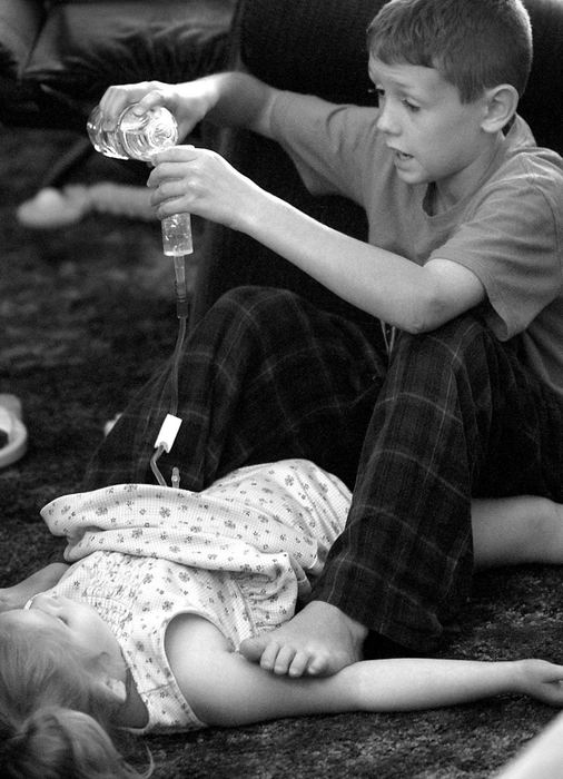 Award of Excellence, Photographer of the Year - Michael E. Keating / Cincinnati EnquirerAudrianna's brother Nick uses his feet to restrain Audrianna as he gives her water through her g-tube.  Audrianna will grab at her brother and might pull the tube out of her stomach if he does not hold her down.