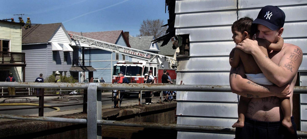 First Place, Photographer of the Year - Dale Omori / The Plain DealerJerry Thomas holds his 1-year-old son, Jerry Jr., after a fire forced them from their multifamily home at left on West 85th Street, near Franklin Boulevard, yesterday morning. Cleveland fire officials said the fire started in an upstairs suite and spread to the roof of the house next door. The blaze left four adults and three children, including the Thomas family, homeless. Damage was estimated at $70,000.