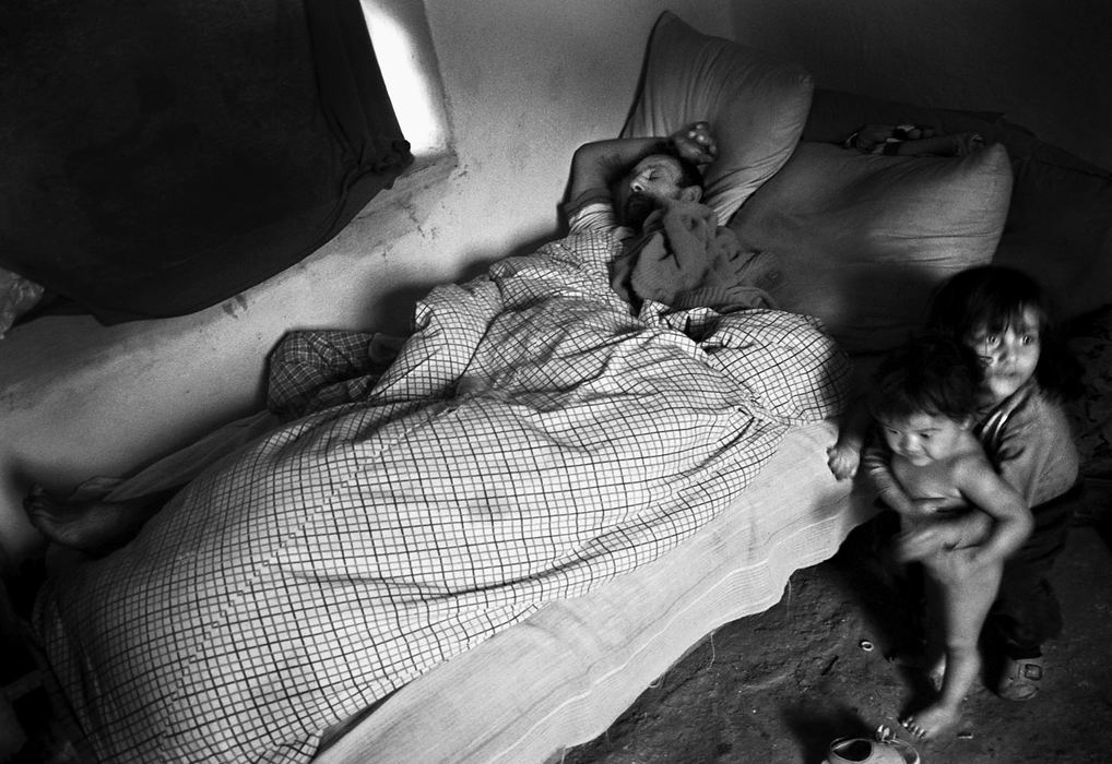 Second Place, Photographer of the Year - Greg Ruffing / FreelanceLeft alone while their mother has gone out to find food, two small children play at their father's bedside as he rests in the early morning.