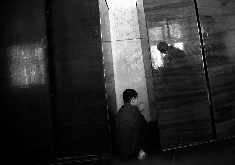 Second Place, Photographer of the Year - Greg Ruffing / FreelanceKristina, age 15, squeezes between two cabinets trying to hide from nurses. Undereducated and short-staffed, nurses are often unable to provide quality care for the children.