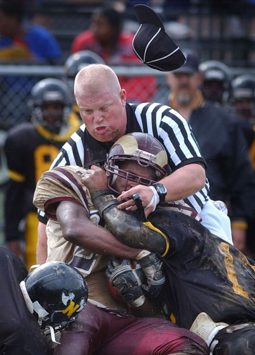 Second Place, Sports Action - Lew Stamp / Akron Beacon JournalUmpire Matt Byer and Garfield's Norman Taylor (27) are brought down by North's (21) RaShawn Batties and (17) Joe Copeland during a City Series game at Buchtel High School's Griffin Stadium, September 26, 2003.