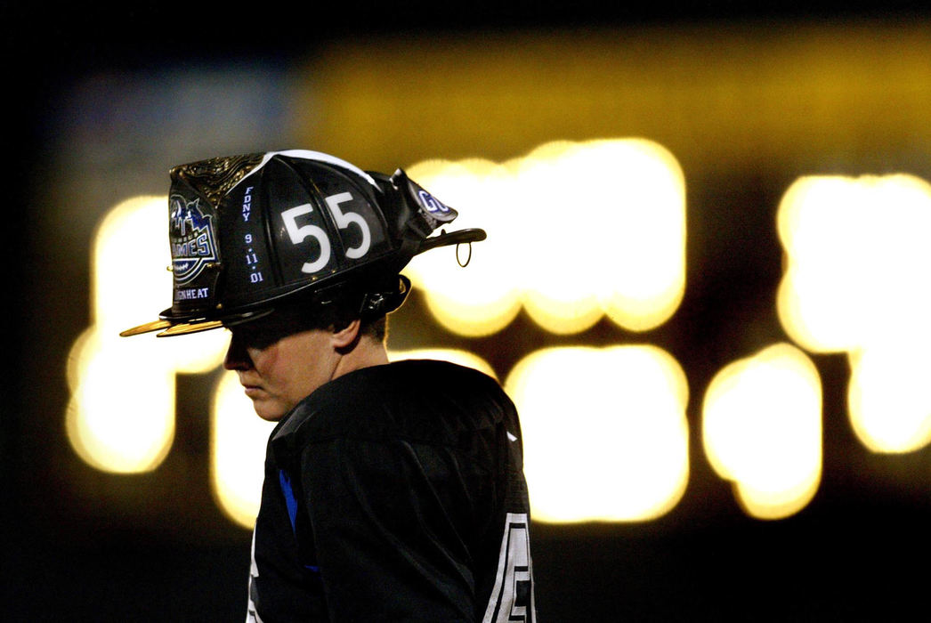 First Place, Sports Picture Story - Fred Squillante / The Columbus DispatchSidelined for the season because of a back injury, the Flames' Laura Kerr stands on the sidelines during a game against the D.C. Divas. She wears a firefighter's helmet which has her number and the Columbus Flames logo on it. She is a firefighter from Fairborn. 