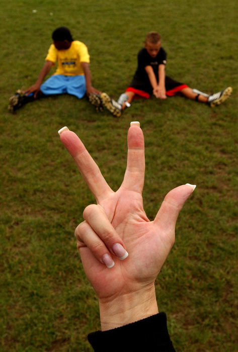 Third Place, Sports Picture Story - David Distelhorst / Akron Beacon JournalSign language interpreter Karline Caslow signs for Terrel, left, and Sandro as the team counts off while stretching at practice. An interpreter is on hand for practices and games to communicate between the two and the coach.