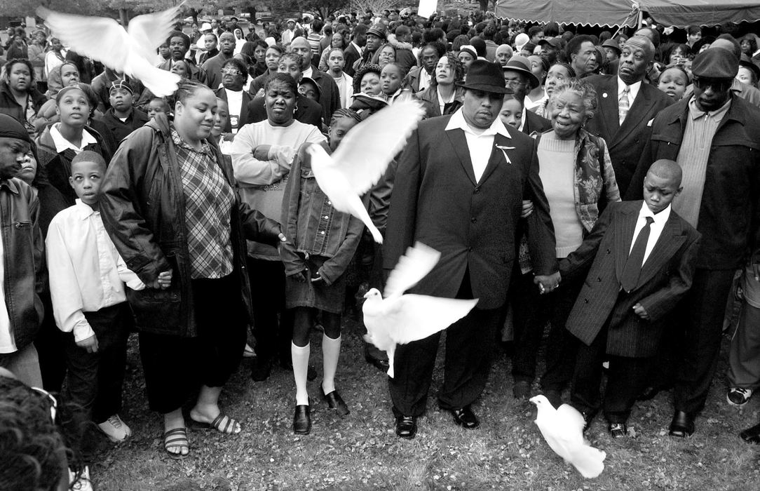 Third Place, Team Picture Story - John Kuntz / The Plain DealerShakira Johnson's step-father, Ralph Randle, in the center wearing a hat, watches doves released in his daughter's honor at Lake View Cemetery. Ralph holds son Ralph Jr.'s hand. Shakira's mother waits in a limousine, overcome with grief.  