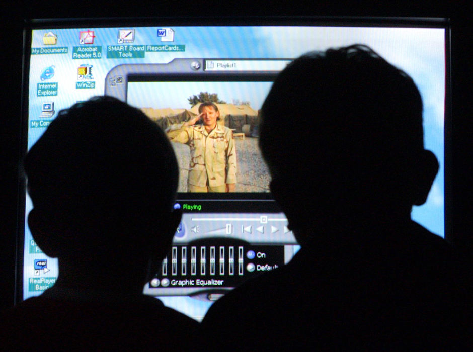 Second Place, War in Iraq - Chris Stewart / Dayton Daily NewsBrothers Cole. left, and Richard Salisbury watch a video recorded by their mother, Beth Salisbury, who is now serving in Iraq.  Richard, 7, and Cole, 6, of Lewisburg, Ohio, joined their Tri-County North classmates the next day for a Veterans' Day program featuring the video.