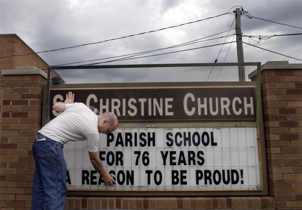 Award of Excellence, Feature Picture Story - Gus Chan / The Plain DealerDan Kever puts up the sign in front of St. Christine School on the day of graduation, June 2, 2004.  The school was graduating their kindergarteners in the morning and the eighth graders during an evening mass. 