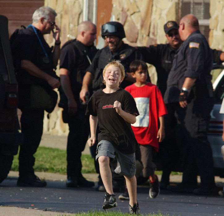 Award of Excellence, News Picture Story - Warren Dillaway / The Star BeaconChildren play near a basketball court where SWAT team members prepared for the possible storming of an apartment where Paul Ganyard had barricaded himself. Ganyard was wanted on an outstanding warrant and claiming he would not be taken alive.