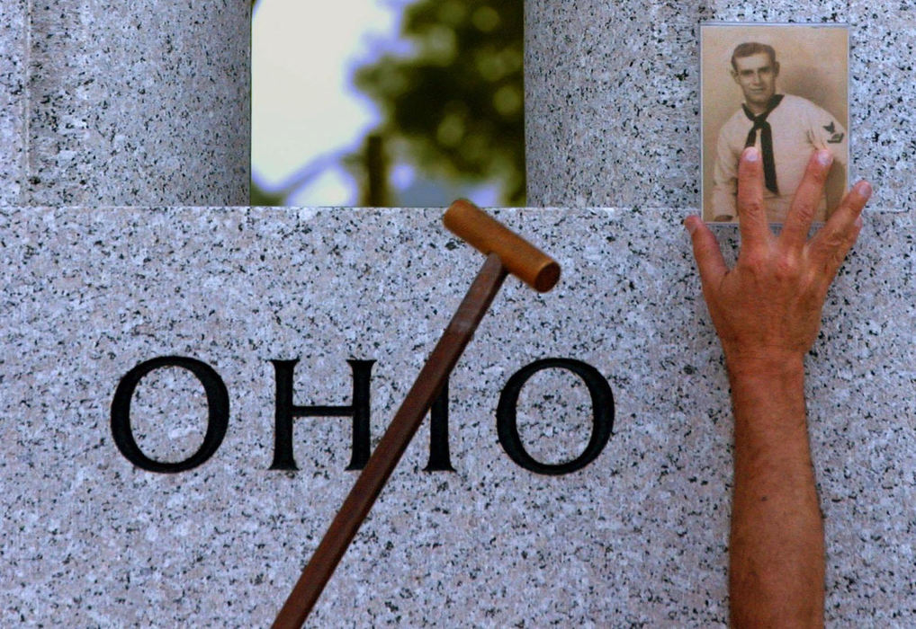 First Place, News Picture Story - Joshua Gunter / The Plain DealerWith the assistance of a cane,  a hand reaches high to place a photograph of Robert E. Gregson on the Ohio pillar at the World War II Memorial, May 28, 2004 in Washington D.C. Tammy Getz brought the picture of her grandfather, who served in the Navy in the Pacific during the war, but was unable to put it up herself. Robert Gregson was from Greenville, Ohio. The man who placed the photo was unidentified. 