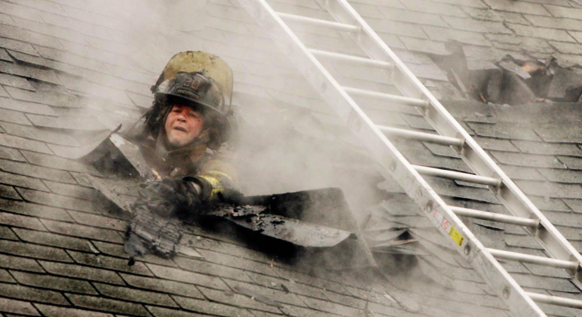 First Place, Photographer of the Year - John Kuntz / The Plain DealerCleveland firefighter Bill Lestock with station 20 vents the roof of a duplex from inside the home at 3424 W. 50th Street in Cleveland where an upstairs fire destroyed the top of the duplex October 20, 2004.  The cause of the fire is under investigation and no one was reported injured in the fire.