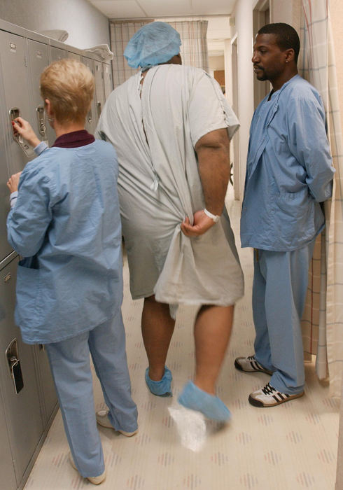 First Place, Photographer of the Year - John Kuntz / The Plain DealerChip dons the hospital covering and holds the back of it as he squeezes his way through two hospital technicians.  The gown was the largest the hospital had and it was too small.
