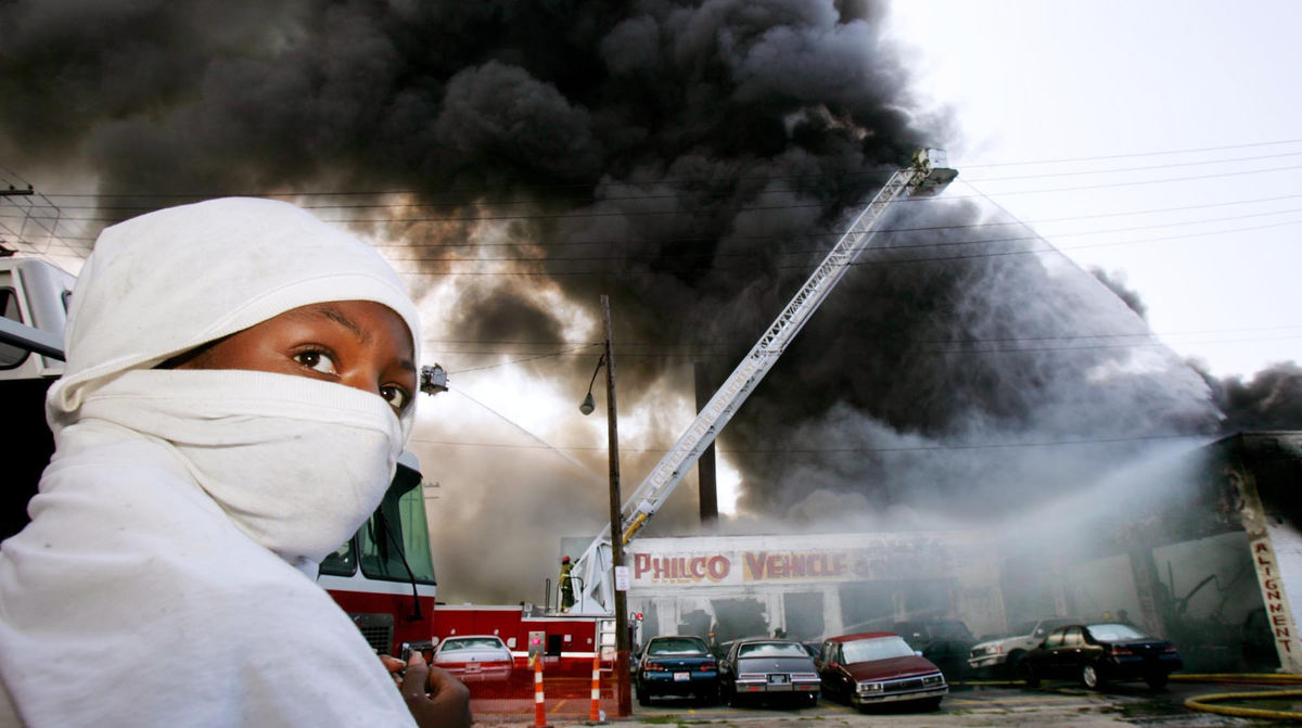 First Place, Photographer of the Year - John Kuntz / The Plain DealerTawana Haywood,14, of Cleveland wears a T-Shirt wrapped over his head to filter the immense amount of smoke caused by a fire at Horn Auto Inc. at the intersection of Carnegie and E. 71st. as Cleveland firefighters battle the blaze August 14, 2004.  The fire destroyed the building and 60 cars in and around the lot to be serviced and it is unknown what caused the fire.  The auto service shop was closed at the time the fire started and there were no reports of injuries.   