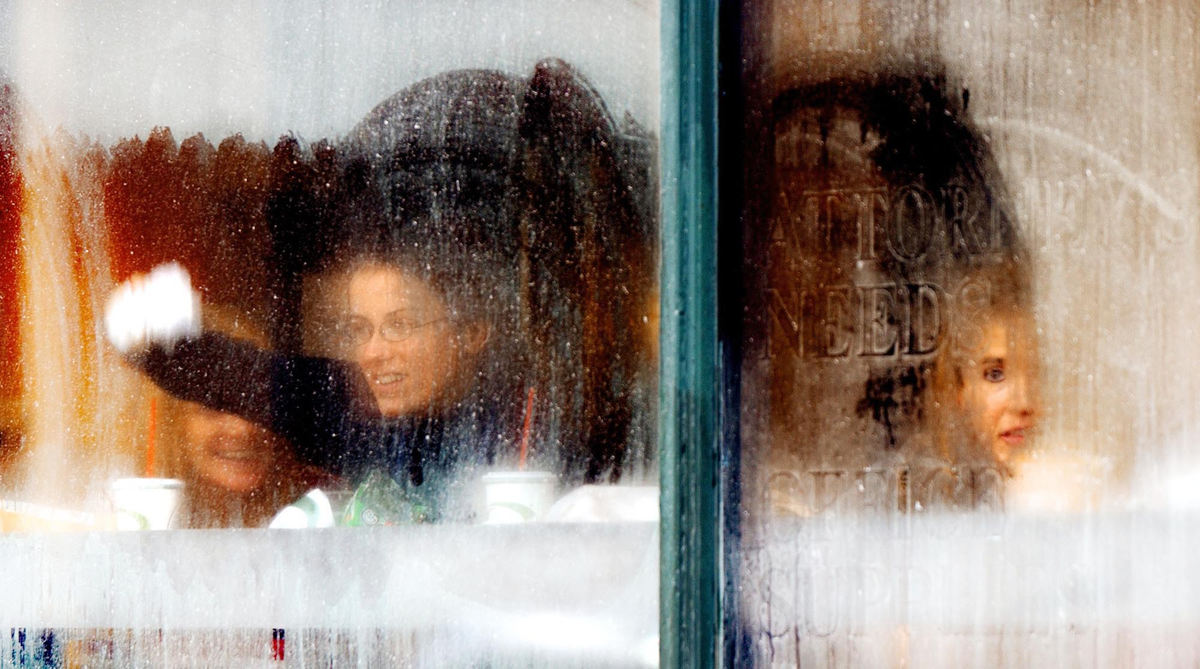 First Place, Photographer of the Year - John Kuntz / The Plain DealerMolly Dalton wipes the condensation off the windows inside the Quizno Restaurant on W. 3rd and Lakeside Avenue so her lunch time co-workers, sister Amy Dalton (left), Bonnie Sara and Roberta Arnold (not seen) can see the cold pedestrians hurry by the window January 7, 2004 in Cleveland.  The temperature with wind chill dipped into the single digits this morning. 