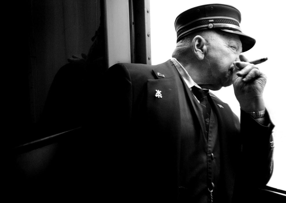 Second Place, Portrait/Personality - Meggan Booker / Cincinnati EnquirerTed Hughes smokes a cigar and looks down the track on the Cincinnati Railway Co. excursion to the Raspberry festival in Batesville, Ind.  Hughes, a 50-year railroad employee and former conductor, was a guest on the train, but he wore his conductor's uniform.  "Once you get it in your blood, you're stuck," Hughes said of trains.  "I love trains still."  Hughes is 82 and lives in Anderson Township. 