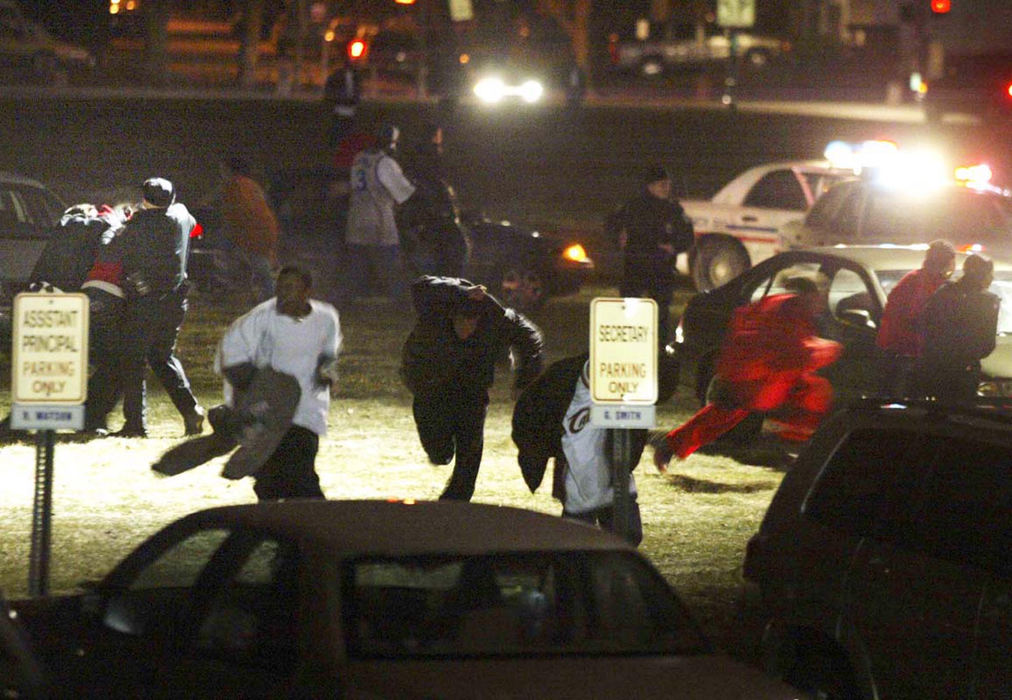 Award of Excellence, Spot News over 100,000 - Jame D. DeCamp / The Columbus DispatchColumbus Police Officers (left) wrestle with a student involved in a fight as others involved run for cover outside Independence High School, January 13, 2004. Several fights broke out following the basketball game against rival Walnut Ridge and there was also a report of a car hit by gun fire.  The light from above is from the CPD chopper.