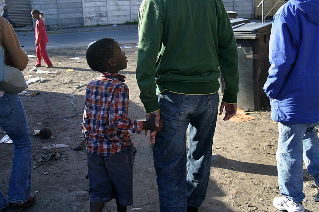 First Place, Student Photographer of the Year - Samantha Reinders / Ohio UniversityThe Begging Factor - A local kid tugs at the hand of Rashid Mosajee (American) as he and the rest of the foreigners on his tour of Langa Township stroll around the squalor of the hostel dwellings. Begging is highly discouraged by the tour operators but, without fail, kids will take any opportunity given to them to ask for money or sweets. 