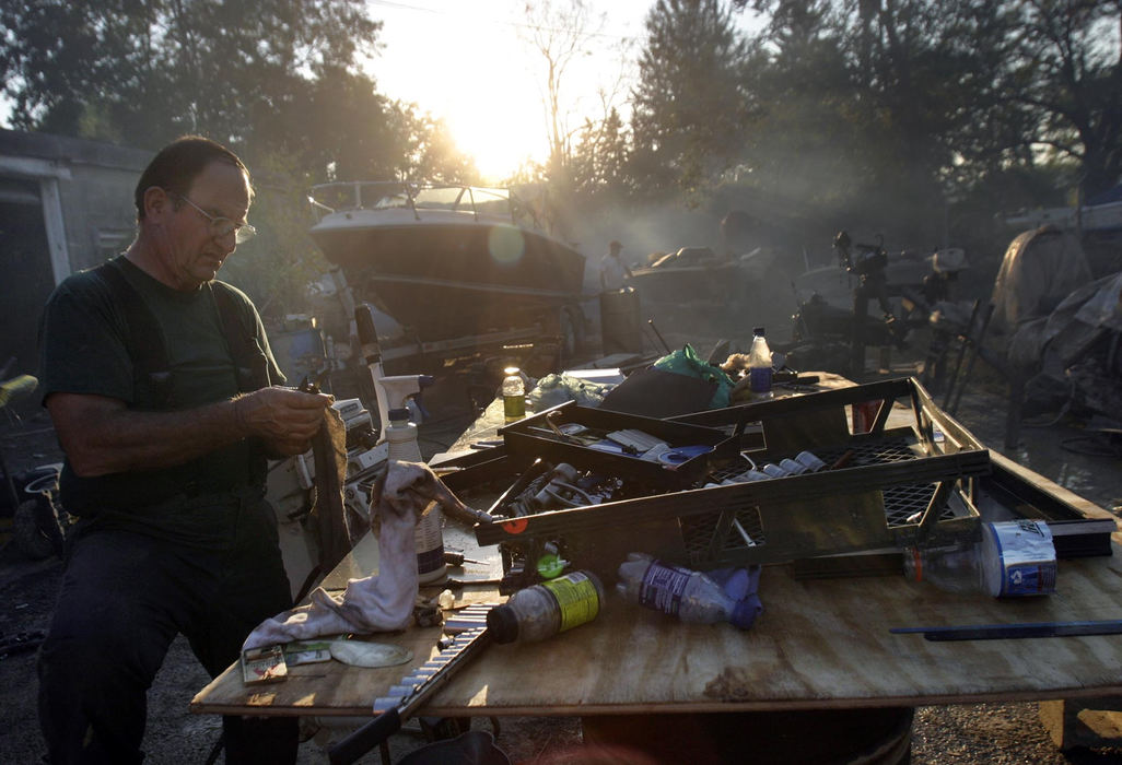 Second Place, Student Photographer of the Year - Michael P. King / Ohio UniversityWith his parking lot converted into a clean-up center, John Schwarzel, owner of Schwarzel Marine, sorts through a mess of boat engine parts and tools that were submerged in floodwater, wiping as he goes, September 22, 2004. Schwarzel's friends and frequent customers also came and volunteered their time to help make order. Almost two weeks after the waters receded, less than half of the cleanup was complete. 