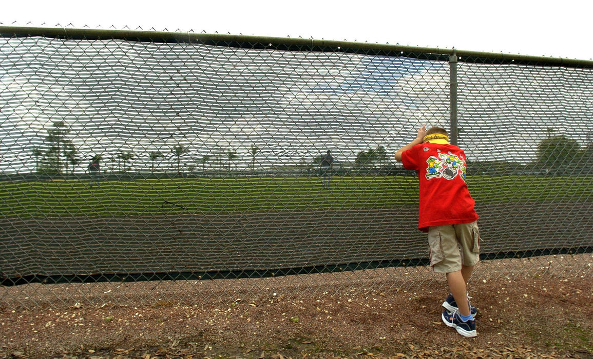 Third Place, Sports Picture Story - Chuck Crow / The Plain DealerA youngster peers through fencing while waiting for a home run ball on practice diamond #1 at Chain of Lakes Park in Winter Haven, Fla.  Anyball hit over the fence is fair game.
