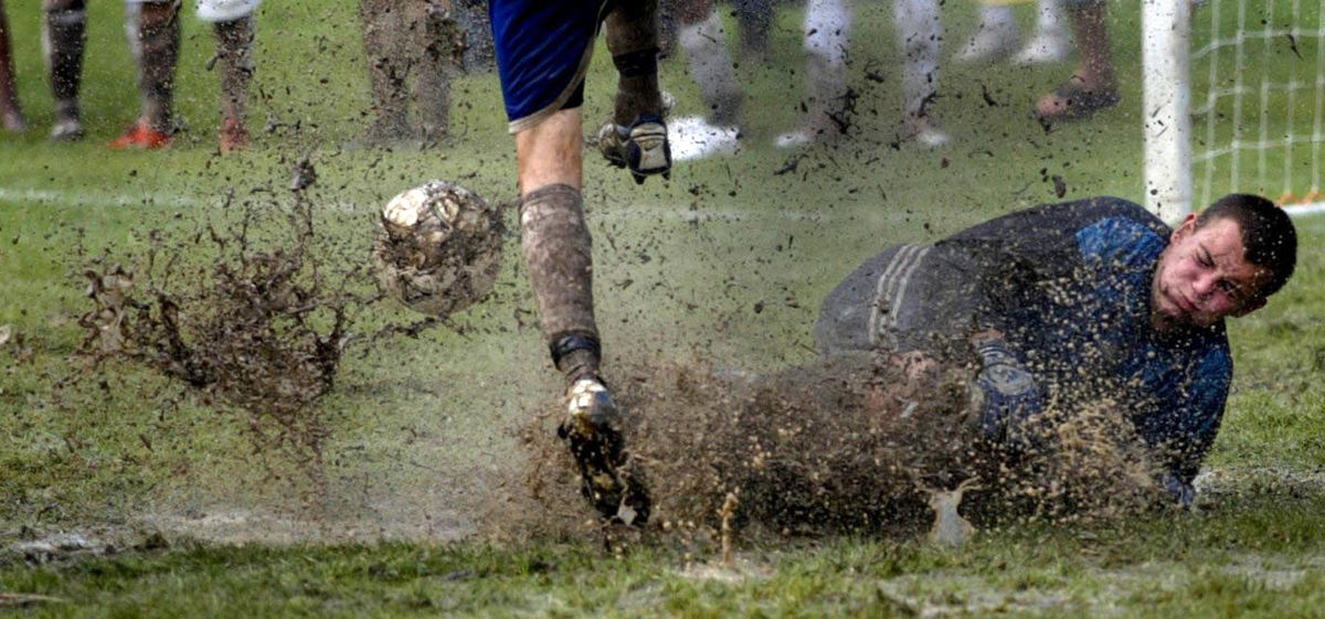 Second Place, Team Picture Story - Tracy Boulian / The Plain DealerFilar Maciej, a goalie for Krosno, Poland, slides during a waterlogged soccer game.