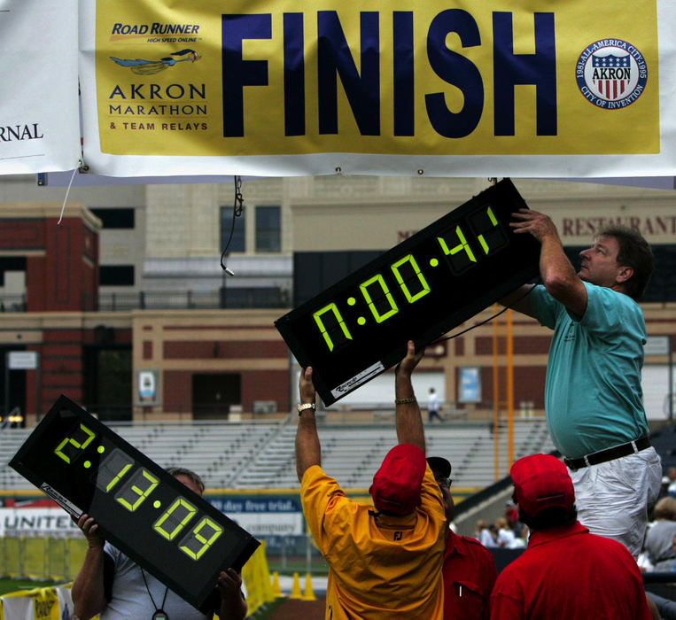 First Place, Team Picture Story - Ed Suba Jr. / Akron Beacon JournalRace officials try and quickly change a faulty time clock at the finish line in Canal Park during the 2004 Road Runner Akron Marathon on October 2, 2004. 