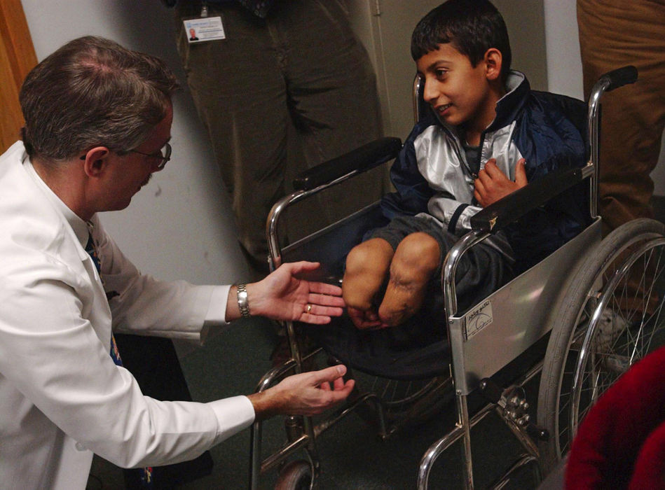 Second Place, Feature Picture Story - Karen Schiey / Akron Beacon JournalDr. Paul  Fleissner, an orthopedic surgeon at the Crystal Clinic in Bath Township, examines what remains of Majid's legs after he was injured in a roadside bomb explosion in his home country of Iraq. Majid's five months of medical care in the United States was organized and funded by the Palestine Children's Relief Fund founded by Majid's host family, Steve and Huda Sosebee of Kent.
