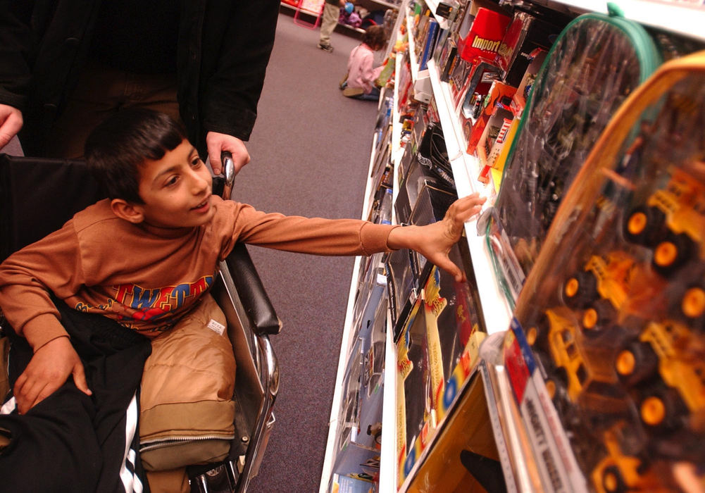 Second Place, Feature Picture Story - Karen Schiey / Akron Beacon JournalMajid is overwhelmed by seeing so many toys in a mall toy store as he is pushed by his host father Steve Sosebee.