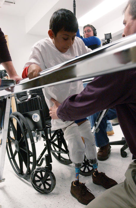 Second Place, Feature Picture Story - Karen Schiey / Akron Beacon JournalMajid takes his first steps on his prosthetic legs with the help of parallel bars and Yankee Bionics prosthetist  Kevin Montini.