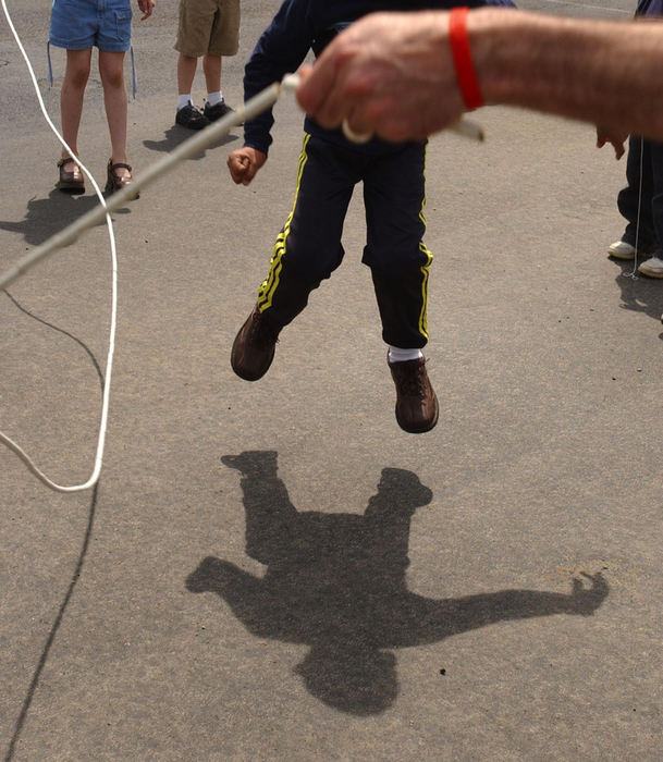Second Place, Feature Picture Story - Karen Schiey / Akron Beacon JournalMajid's shadow dances across the blacktop of the playground as he jumps a rope twirled by a student and physical education teacher Shawn Bates during  recess at Holden Elementary School.