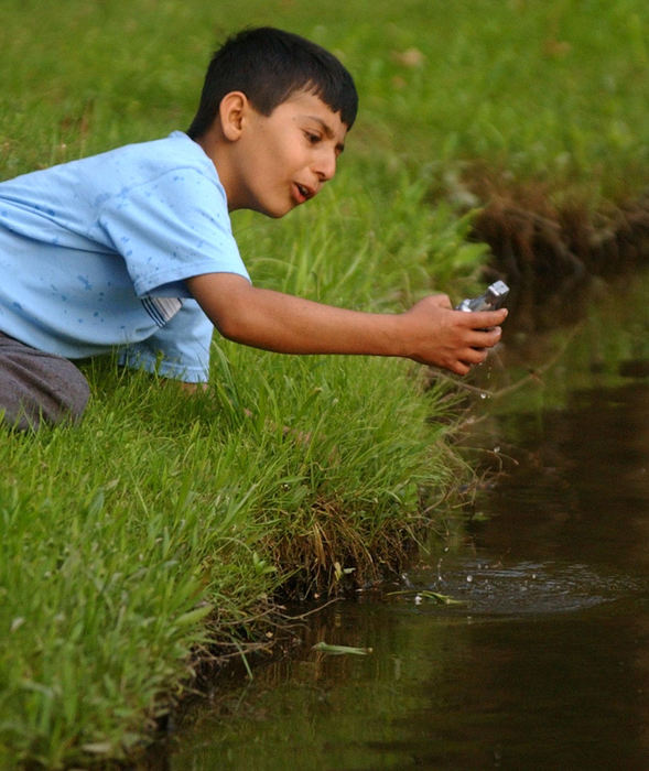 Second Place, Feature Picture Story - Karen Schiey / Akron Beacon JournalMajid pulls a plastic toy hand grenade out of the water at Plum Creek Park during a Holden Elementary School class picnic in Kent.