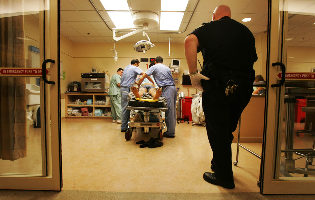 Award of Excellence, Feature Picture Story - Gus Chan / The Plain DealerMetroHealth's Emergency Department is the busiest in the city, handling the most traumatic cases in northeastern Ohio. A security officer watches as a patient is being treated.