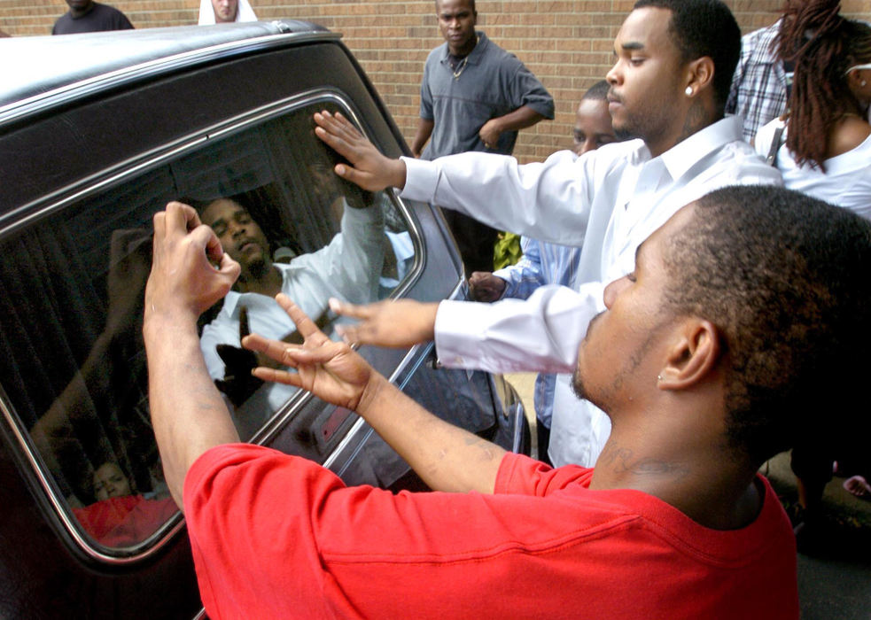 Second Place, General News - Scott Heckel / The RepositoryFriends flash gang symbols at the rear of the hearse that carried 17 year old shooting victim Michael Cheek to the cemetery following his funeral at the Apostolic Faith Assembly in Canton. Local high school football star, Steven Walker, a University of Pittsburgh recruit, was arrested for the murder.