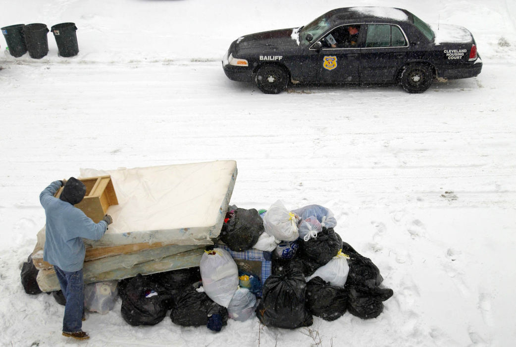 Award of Excellence, News Picture Story - Gus Chan / The Plain DealerA mover stacks trash bags filled with clothing on the tree lawn as bailiff Al Humphrey keeps watch from his car.