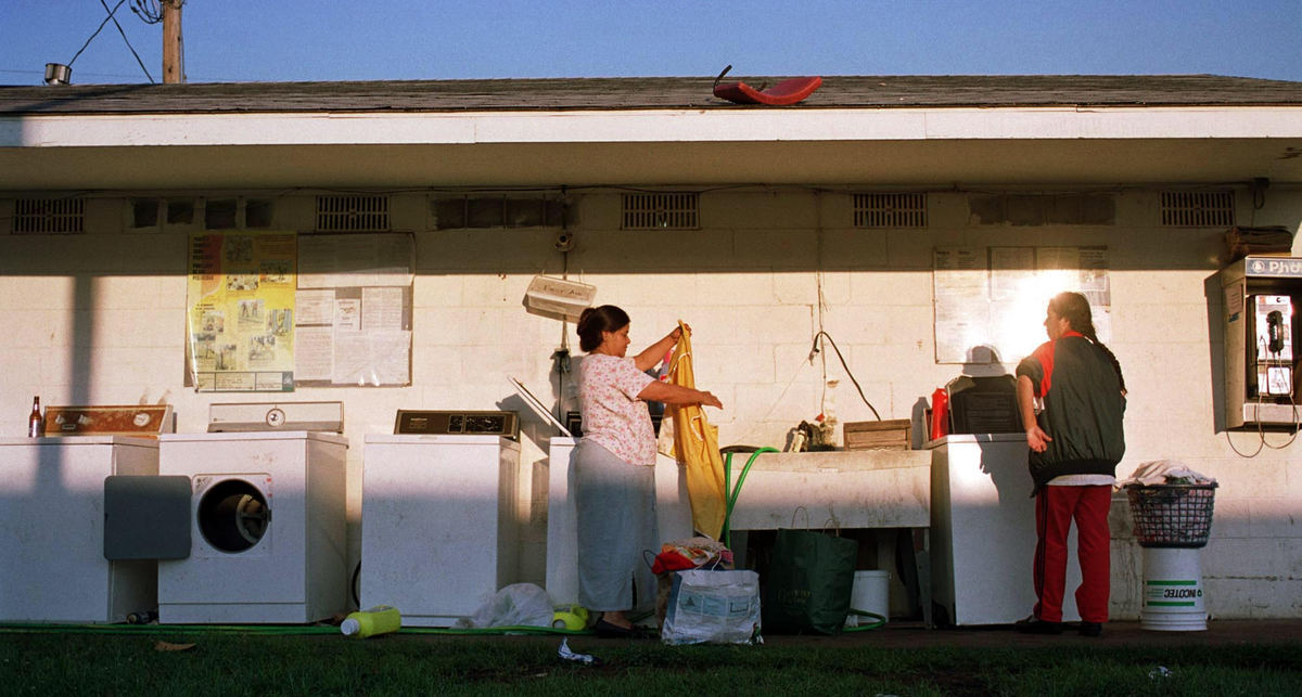 First place, James R. Gordon Ohio Understanding Award - Gary Harwood / Kent State UniversityMigrant women start early as the warm glow of the rising sun greets them while doing laundry in Chapman camp. The outdoor wash area behind the shared bathroom facility is an active place as women care for children and wash clothes prior to preparing food for the noon lunch break. It is the only time when migrants return from the fields during the workday.