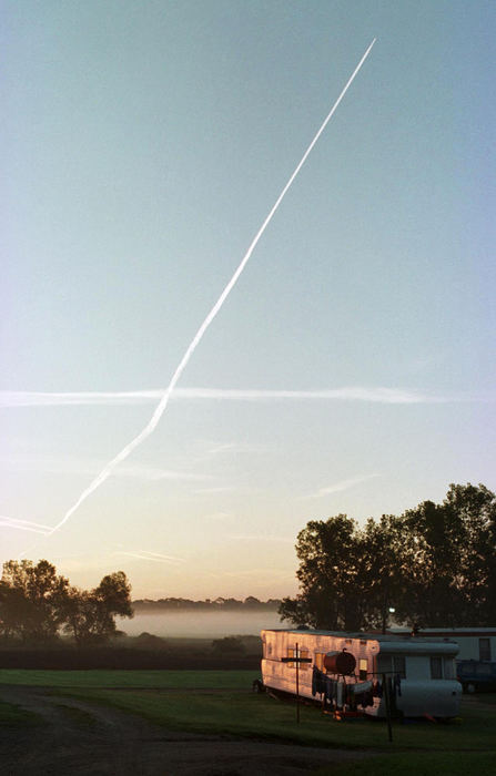 First place, James R. Gordon Ohio Understanding Award - Gary Harwood / Kent State UniversityBefore the workday begins, exhaust trails from an airplane mark the skies as the sun rises over Royer camp. Nearly 300 migrants live in housing camps on the perimeter of the K.W. Zellers and Son family farm. Over the past 10 years, the returning workers and their families have established their own community on the 600-acre farm.