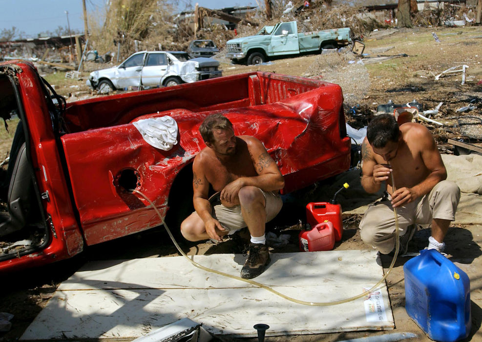 Second Place, George S. Smallsreed Photographer of the Year Award - Greg Ruffing / FreelanceRobert Thompson (right) sucks on a tube to get gas flowing as he, Chester Mayo (left) and David Russell (not pictured) try to salvage gasoline from one of Mr. Russell's trucks that was damaged by Hurricane Katrina when it plowed through their town of Long Beach, Miss. The storm damaged gas availability and prices throughout the South, leaving hurricane survivors scrambling for supplies. 